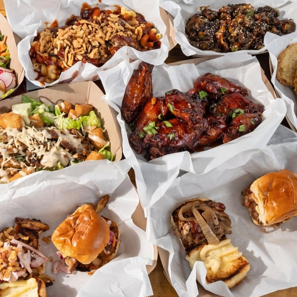 An overhead view of various BBQ dishes, including wings, mac and cheese, salads, and sliders.