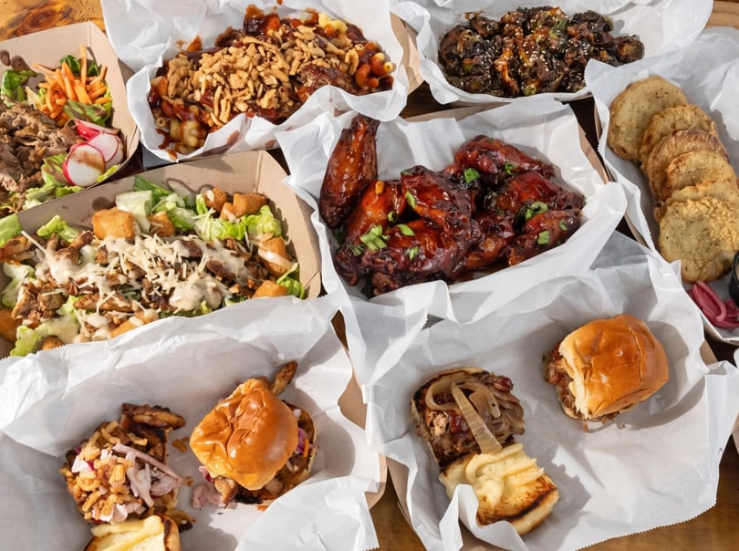 An overhead view of various BBQ dishes, including wings, mac and cheese, salads, and sliders.